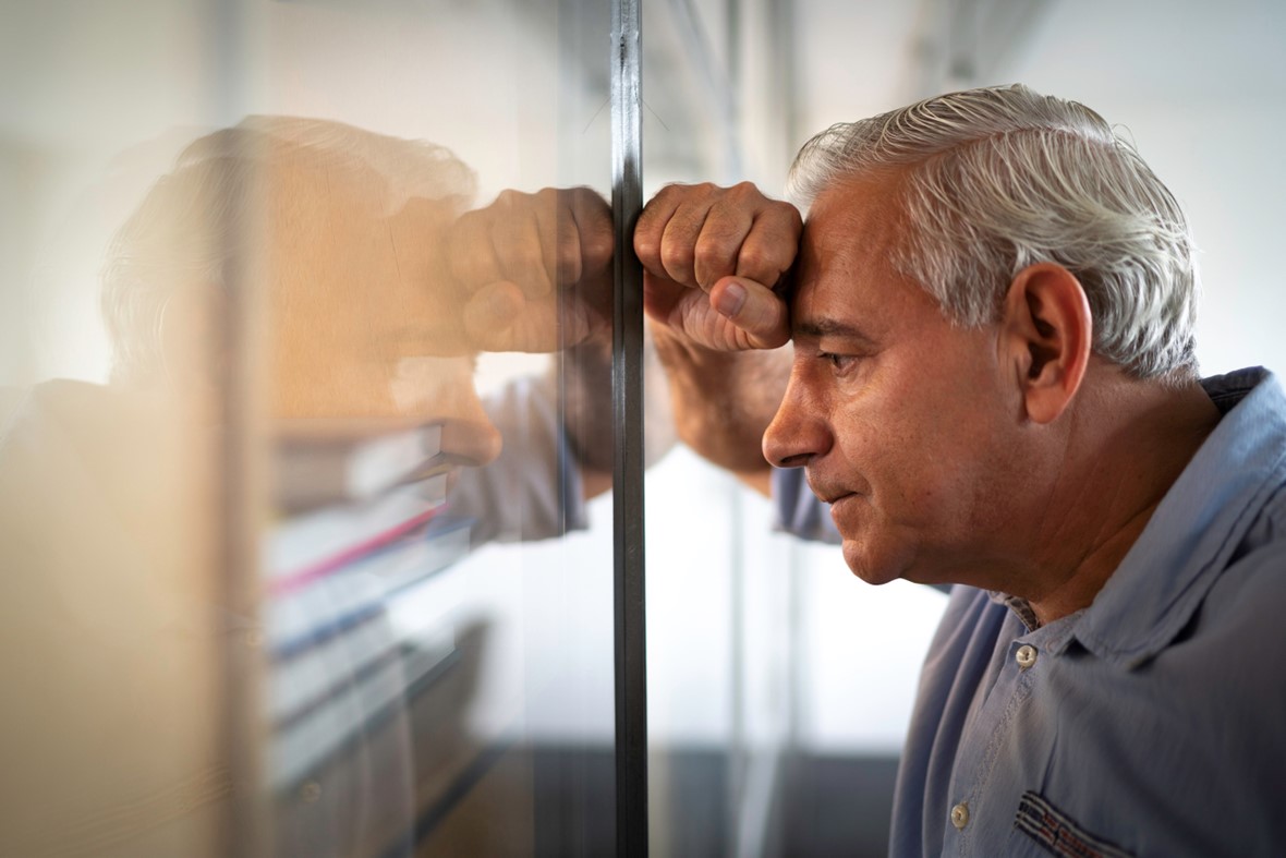 Man leaning against wall in distress.