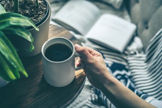 Woman holding a cup of coffee at a desk.